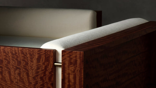 Close-up of Brasa sectional sofa corner in cream bouclé upholstery with a dark walnut wood frame.