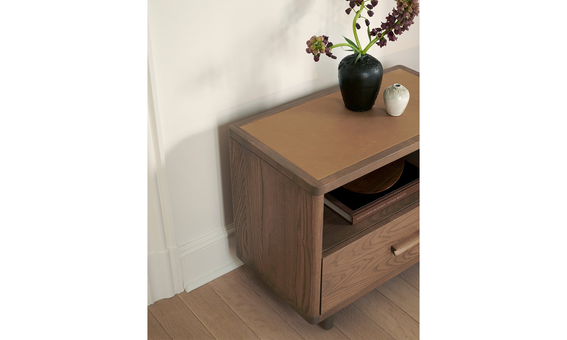 clinton petite brown ash wood nightstand with one drawer and a leather inlay in a bedroom setting