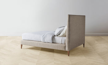 essex bed with upholstered headboard and frame in beige basketweave fabric with wooden legs - back view