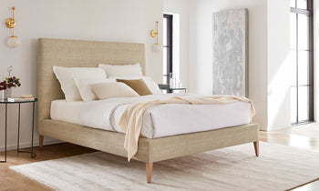 essex bed with upholstered headboard and frame in beige basketweave fabric with wooden legs in a modern bedroom