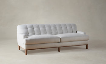 ludlow tufted sofa in white linen with wooden base and legs - angle view