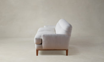 ludlow tufted sofa in white linen with wooden base and legs - side view